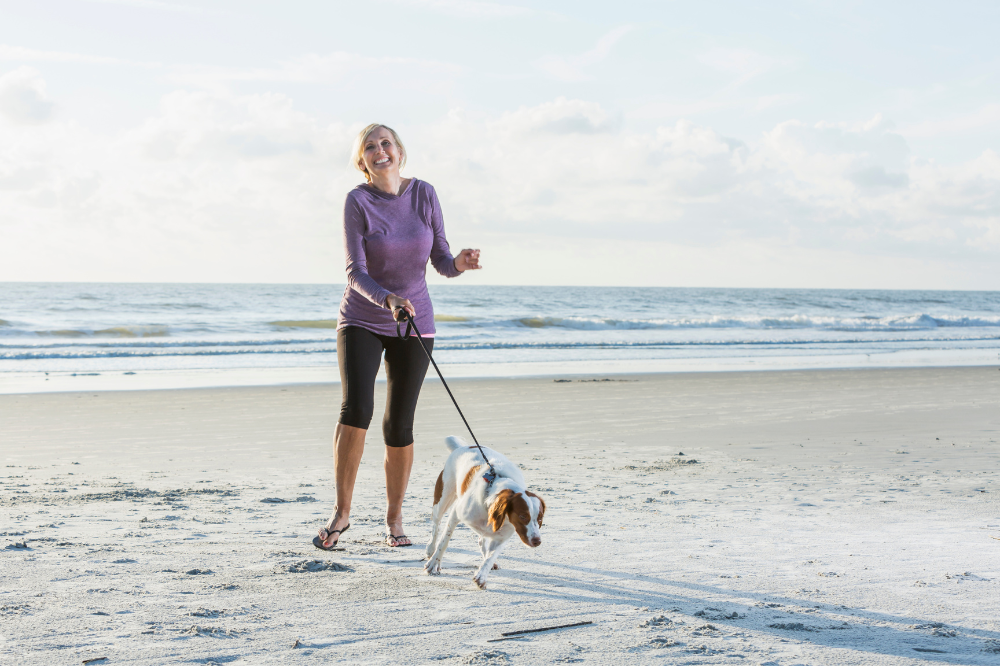 woman walking dog on beach