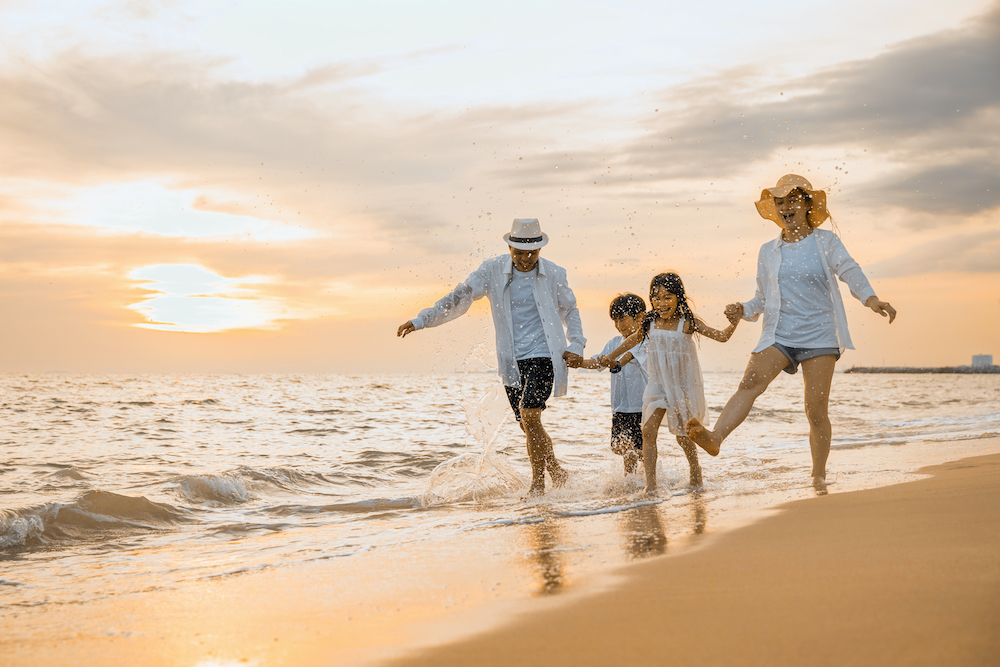 family splashing on beach at oak island